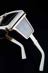 Close-up of Balmain BPS-102F-146 Wonder Boy LTD unisex sunglasses with gold accents and dark lenses, featuring the engraved Balmain Sunglasses logo on the side arm, set against a sleek black background.