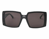Front view of Balenciaga Sunglasses BB0081S 001 99: women’s oversize black square frames with dark lenses and a subtle metallic logo above the nose bridge. The arms stylishly extend backward.