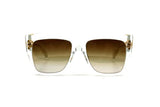The Balmain BPS-100D-56 B-I Unisex Sunglasses feature square clear frames and brown gradient lenses, showcased against a plain white background.