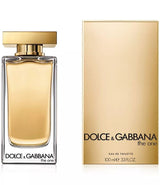 A 3.3 oz bottle of Dolce & Gabbana The One Women Perfume stands by its gold box. The clear glass bottle with a gold cap contains light amber EDT, both showing the Dolce&Gabbana Perfumes name and product title.